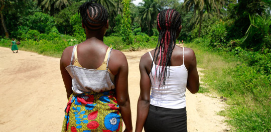 CH1872399 Cousins Kpemeh 18 and Kuji 19 walk home hand in hand in Kailahun Sierra Leone