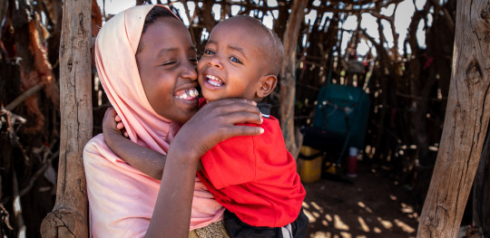 CH11157146 Close up of Faduma, 10 as she holds and cuddles her little brother Abdi, year and a half, Somaliland