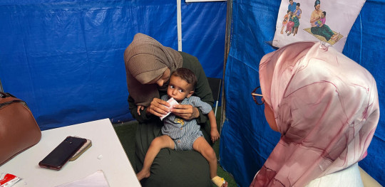 CH11425022 Radwa holds Basma, 1, as she eats from a packet during a consultation
