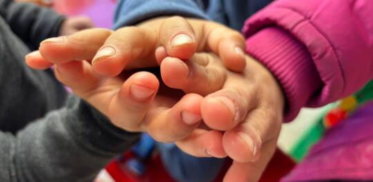 CH11546006 Close up of children's hands in a collective shelter for families forced to flee