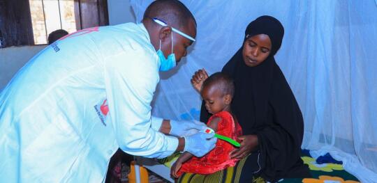 CH11634157 Health worker Aden measures Ayan's (2) mid upper arm circumference (MUAC) at a Save the Children stabilisation centre