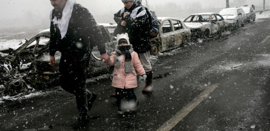 CH1657796 MEDIA USE ONLY A Ukrainian family fleeing Irpin under the snow after the city was hit by shelling