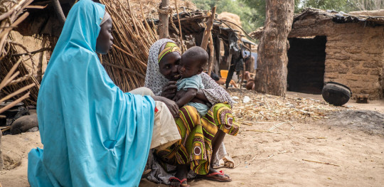 CH1667885 Aisha 30 and Hauwa 15 playing with Bashir one outside their home in a village in Jigawa State Nigeria1