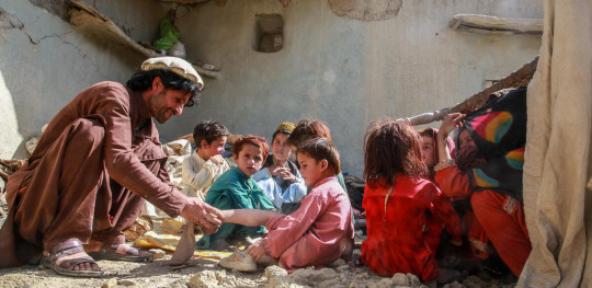 CH1696749 Hakim with his shoe in the remains of their home destroyed by an earthquake in Afghanistan