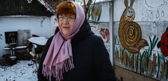 CH1759230 Polinas 68 year old grandmother Larysa standing in the yard of her house in Ukraine in front of a wall that she painted