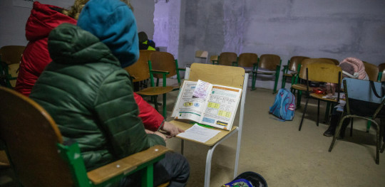 CH1765664 Teacher explains tasks to a student as they take shelter in a school basement during air alert in Chernihiv region Ukraine