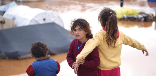 CH1793332 Children playing and walking through flood water and mud in a camp for internally displaced people in Idlib Syria