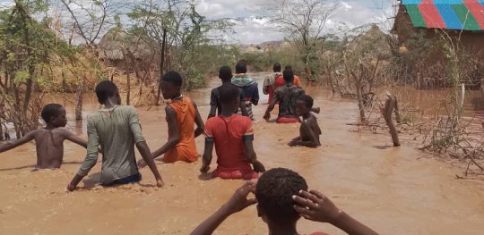 CH1806595 Children wade through flood waters to safety after their village is flooded