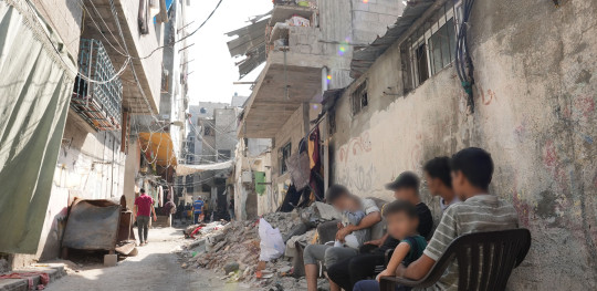 CH1909747 People sitting among a pile of rubble on a street in Gaza