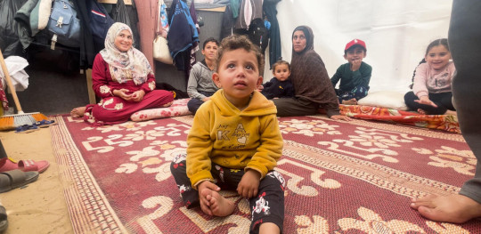 CH1945590 Feras and his grandchildren in the tent where the family shelters in Al Mawasi Khan Younis southern Gaza