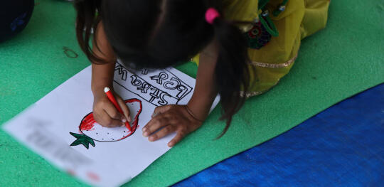 CH262512 A child colours a drawing of a strawberry at a Child Friendly Space in Nuwakot (1)