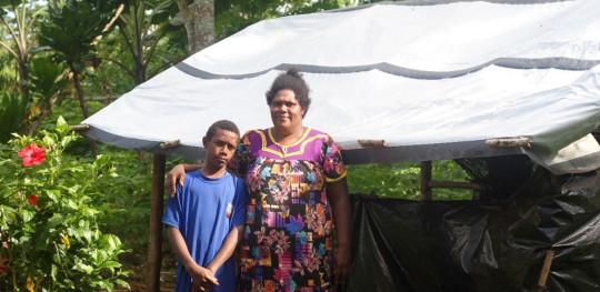 Noa 11 and his mother Emele 39 pictured in front of the tarp they are using for shelter one year on from the twin cycles that damaged their home.