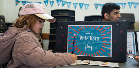 Scarlett 6 tries voting at the Save the Children kids election booth