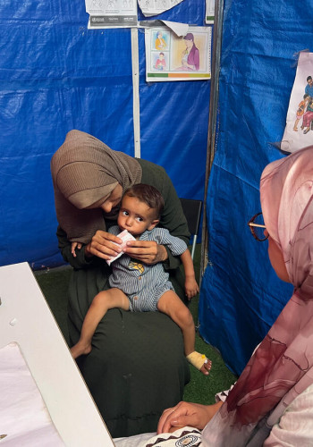 CH11425022 Radwa holds Basma, 1, as she eats from a packet during a consultation