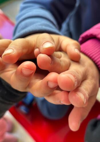 CH11546006 Close up of children's hands in a collective shelter for families forced to flee