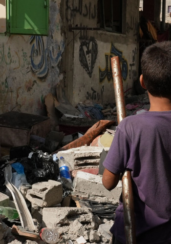 CH1909312 A child standing among a pile of rubble on a street in Gaza v2