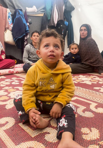 CH1945590 Feras and his grandchildren in the tent where the family shelters in Al Mawasi Khan Younis southern Gaza v2