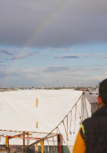 CH1973722 A boy looks at a rainbow over tents in Al Mawasi 1 v2