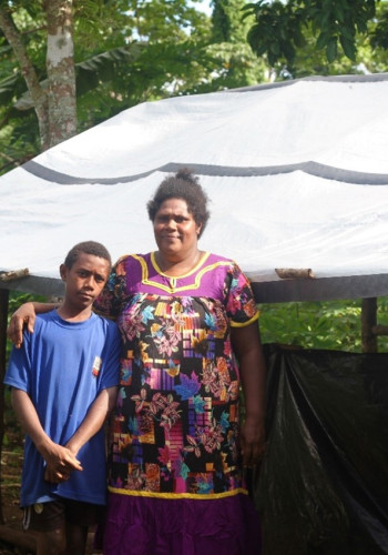 Noa 11 and his mother Emele 39 pictured in front of the tarp they are using for shelter one year on from the twin cycles that damaged their home v2.